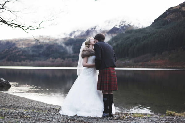 Bride and groom kissing by loch