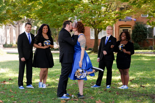 Bride and groom kiss as bridal party watch