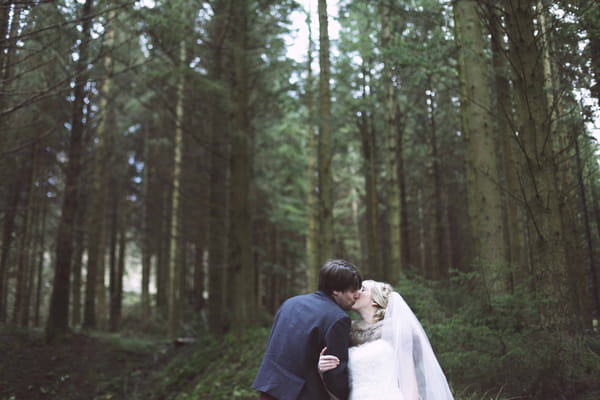 Bride and groom kissing in woodlands