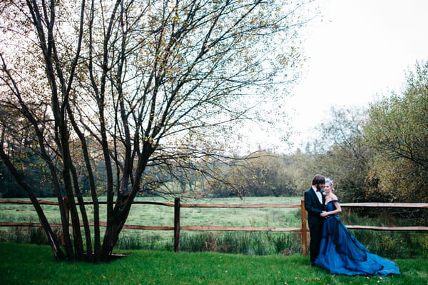 Bride and groom next to fence in field