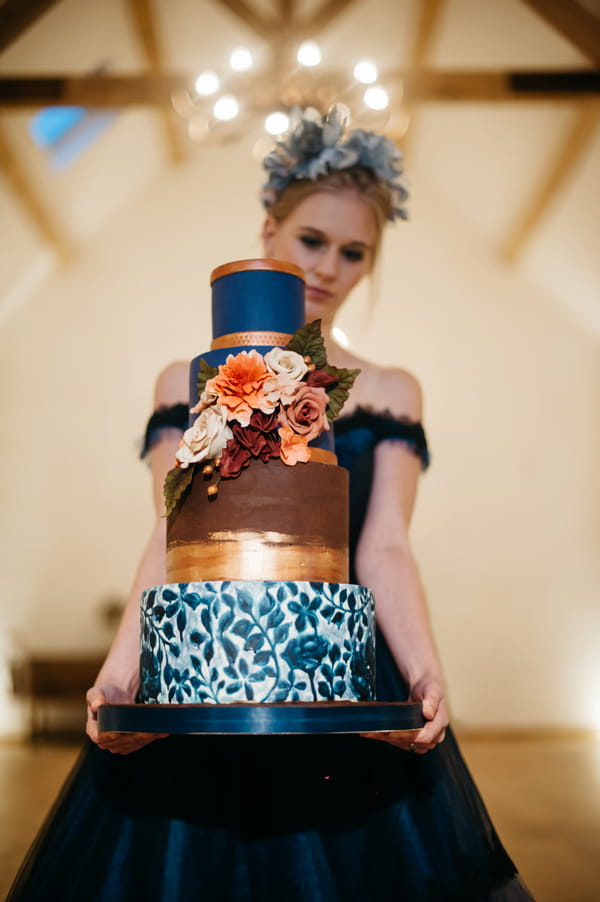 Bride holding blue and gold wedding cake