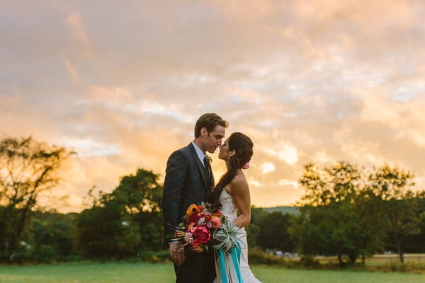 Bride and groom about to kiss in front of dusky sky