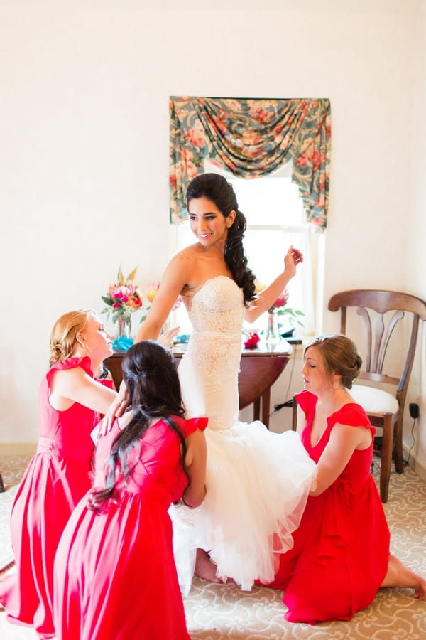 Bridesmaids helping bride into dress