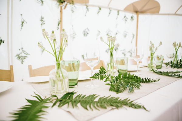 Leaf and bottles of flowers on wedding table