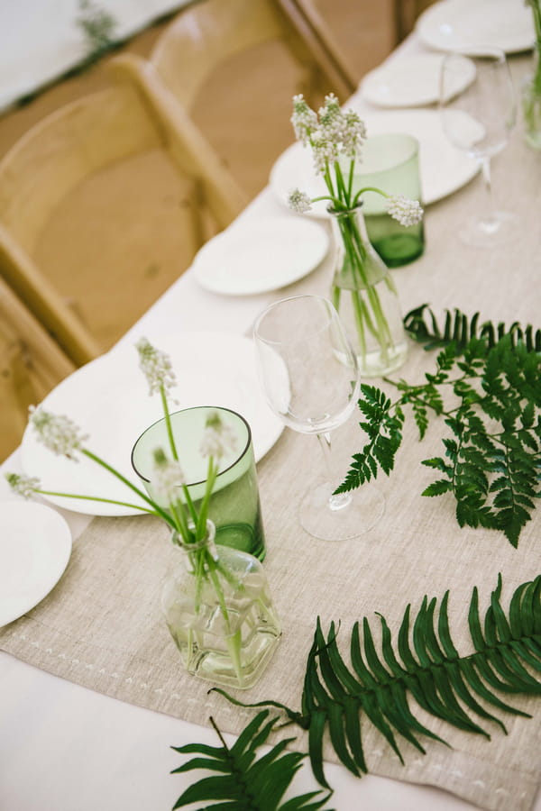 Green glass and bottle of flowers on wedding table