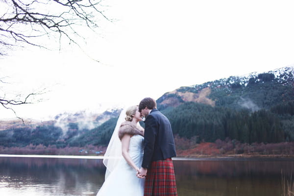 Bride and groom in front of loch and mountains in Scotland