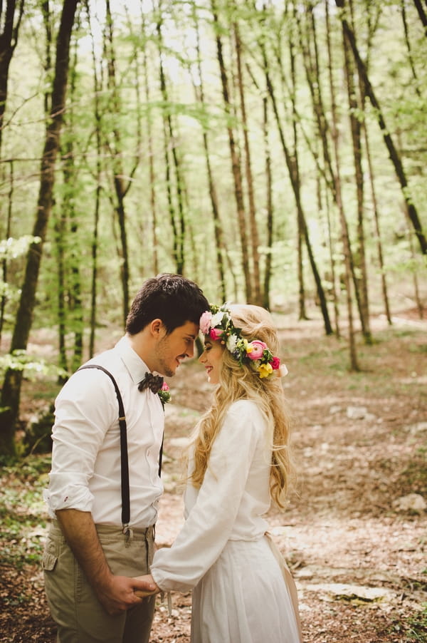 Bride and groom touching heads in woods