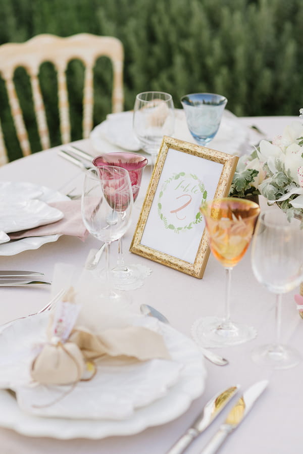 Table number and coloured glasses on wedding table