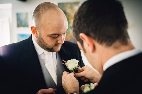 Best man putting buttonhole on groom