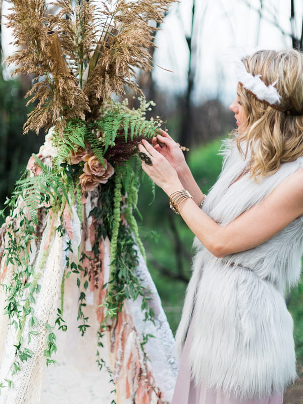 Bohemian bridesmaid touching foliage on tipi