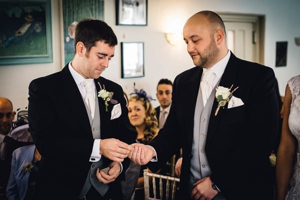 Best man handing groom wedding ring