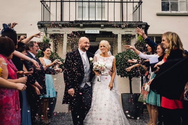 Bride and groom being showered in confetti