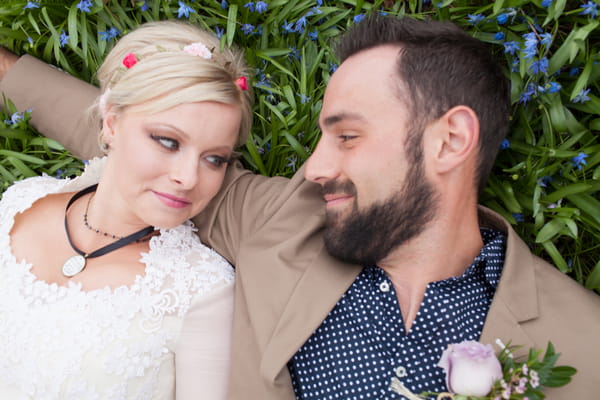 Bride and groom laying in grass smiling at each other