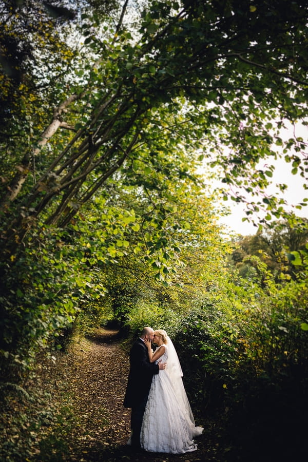 Bride and groom kissing under tree