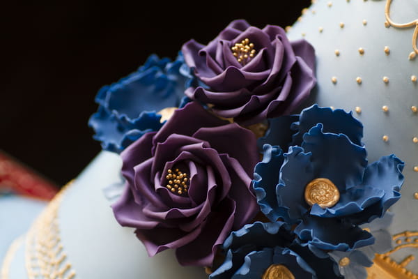 Purple and blue sugar flowers on wedding cake