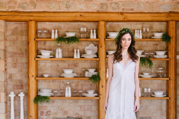 Bride standing in front of shelves of crockery