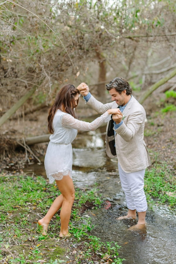 Groom helping bride into creek