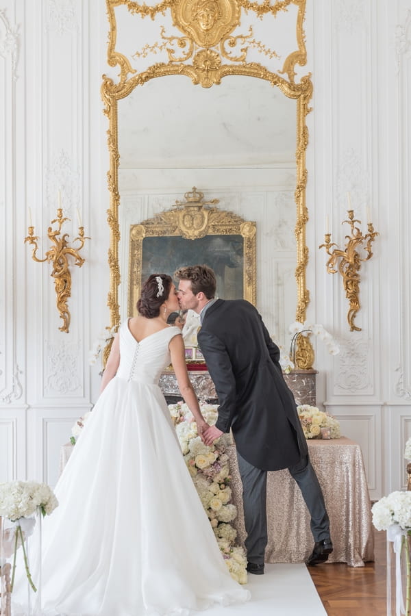 Bride and groom kiss in front of mirror