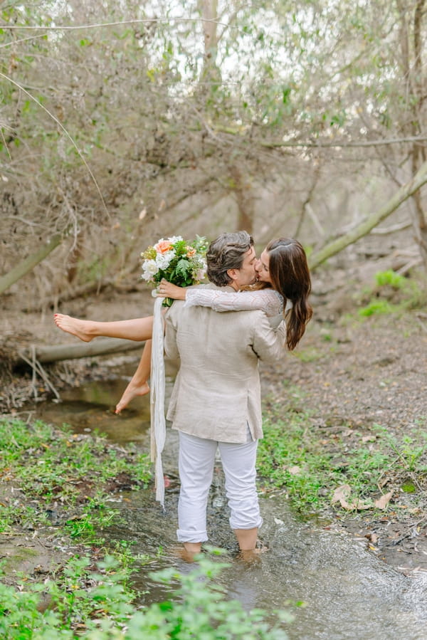 Groom kissing bride in creek