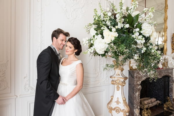 Bride and groom standing by tall floral display