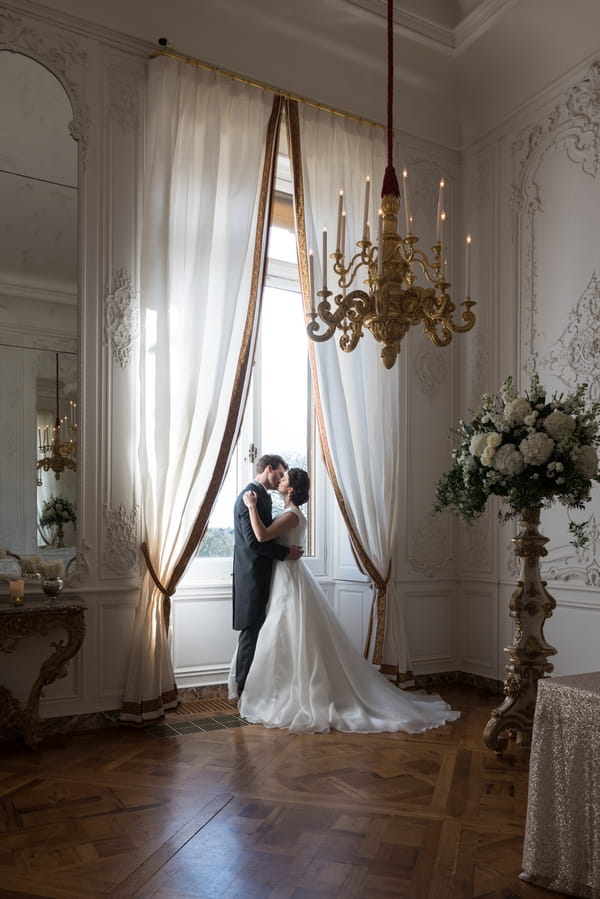 Bride and groom standing by window at Waddesdon Manor