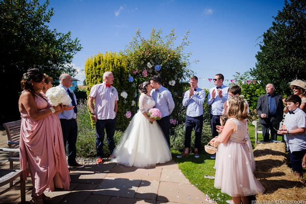 Bride and groom kiss at end of outdoor wedding ceremony