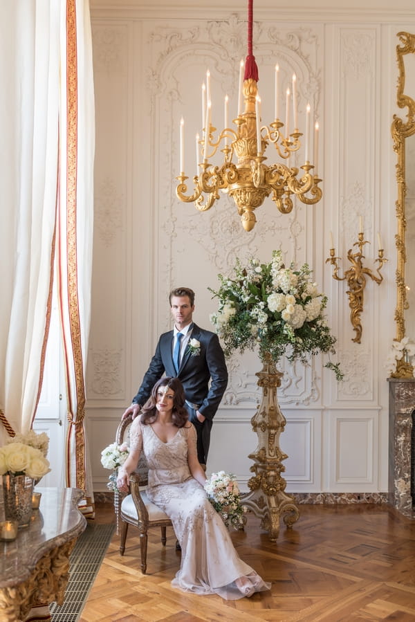 Bride sitting with groom standing behind