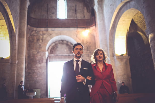 Groom walking arm in arm with mother