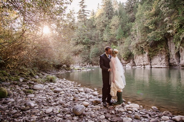 Bride and groom kissing by lake