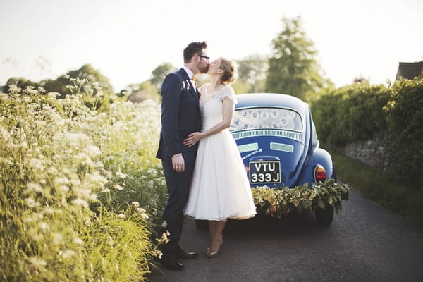 Bride and groom kissing in front of VW Beetle