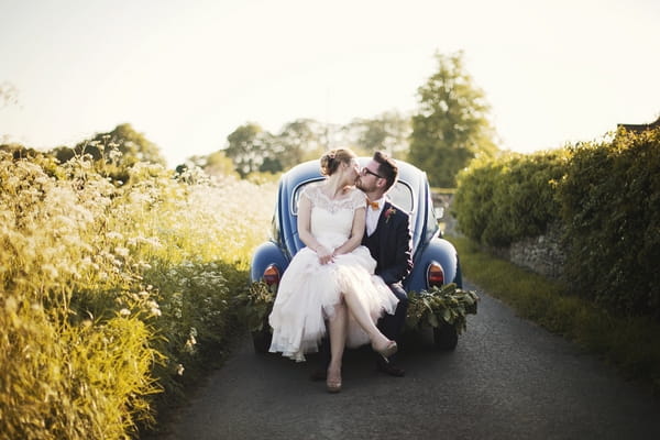 Bride and groom sitting on back of VW Beetle