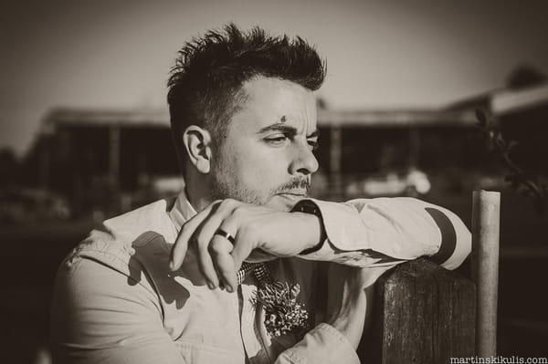 Groom leaning on fence