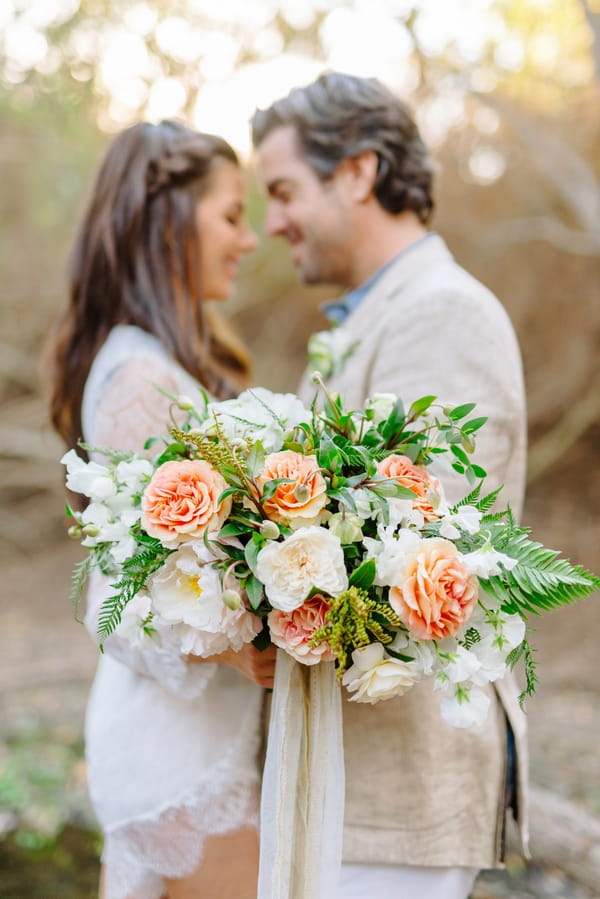 Bride and groom facing each other with large bouquet