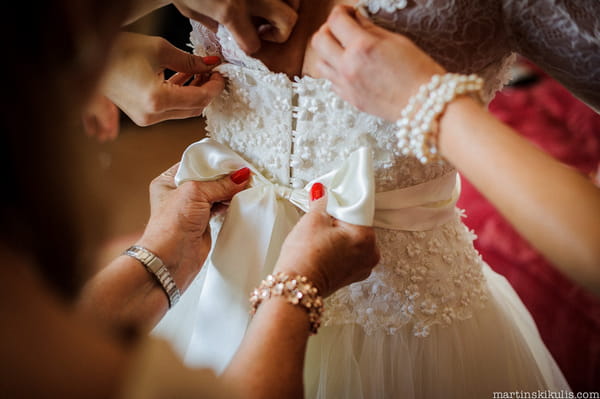 Doing up bow on back of wedding dress