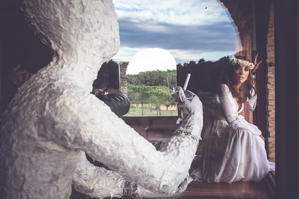 Bride crouching behind white figure with cigarette