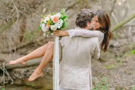 Groom carrying bride in woods