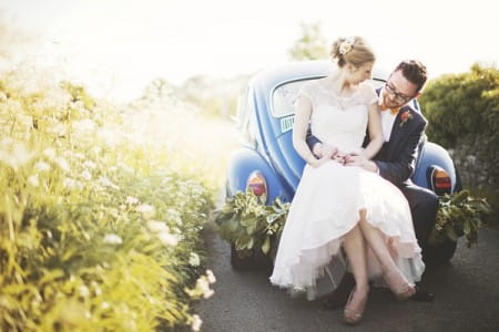 Bride and groom sitting on back of VW Beetle