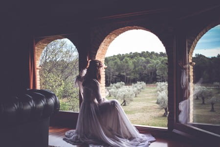 Bride looking out of window before wedding in Girona