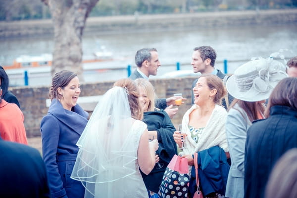 Wedding guests talking to bride by River Thames