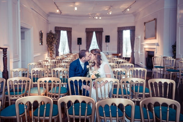 Bride and groom kissing on ceremony chairs