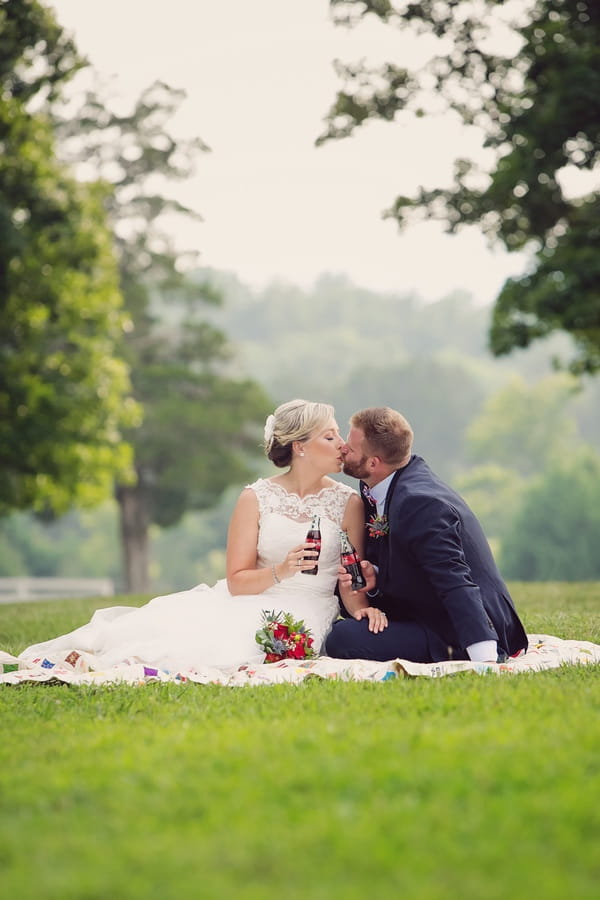 Bride and groom kissing sitting on quilt