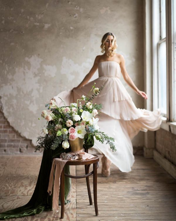 Ballerina bride standing behind chair with bouquet