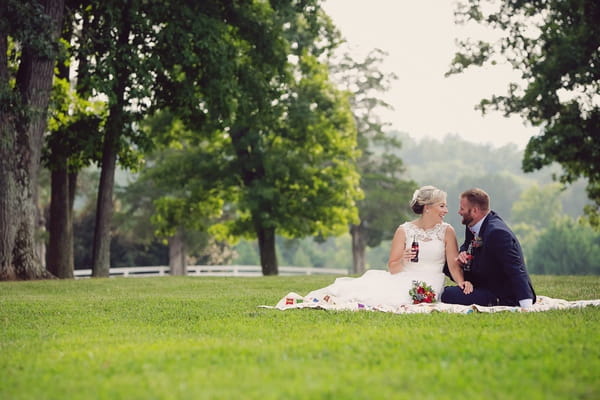 Bride and groom sitting on rug on quilt