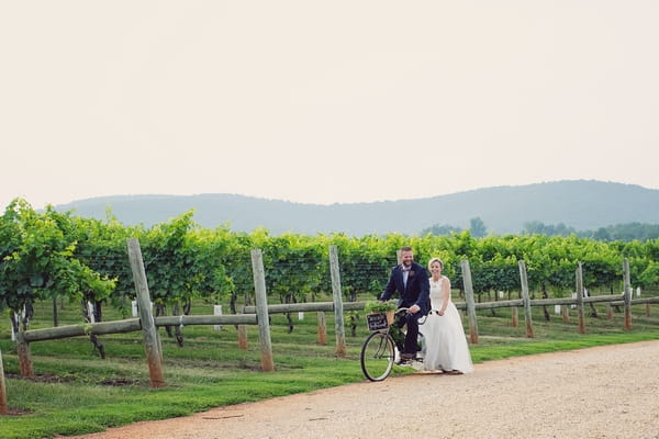 Bride and groom cycling past Keswick Vineyards on tandem