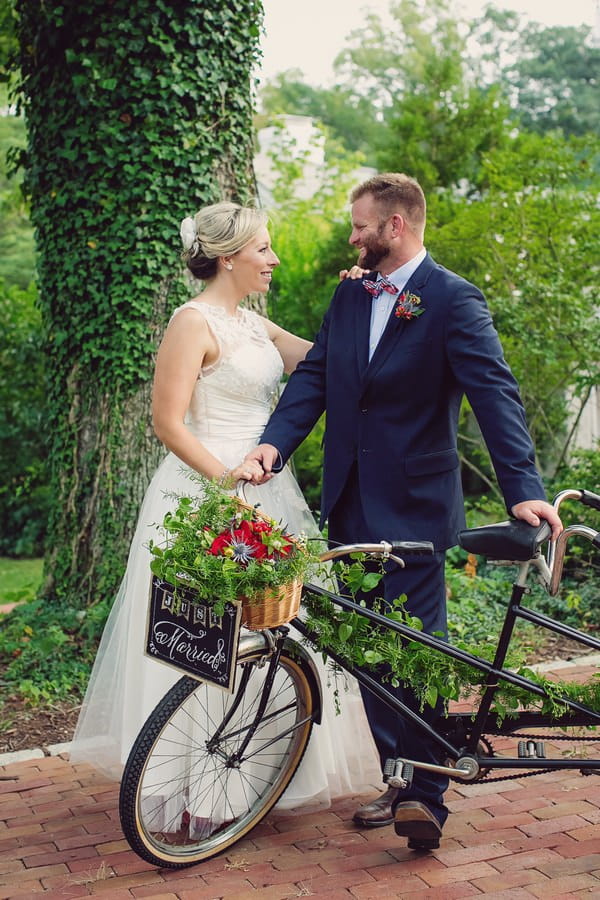 Bride and groom standing with vintage tandem bicycle