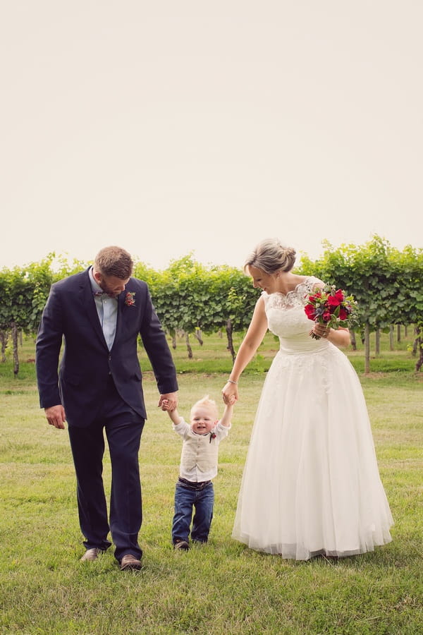 Young pageboy holding hands with bride and groom