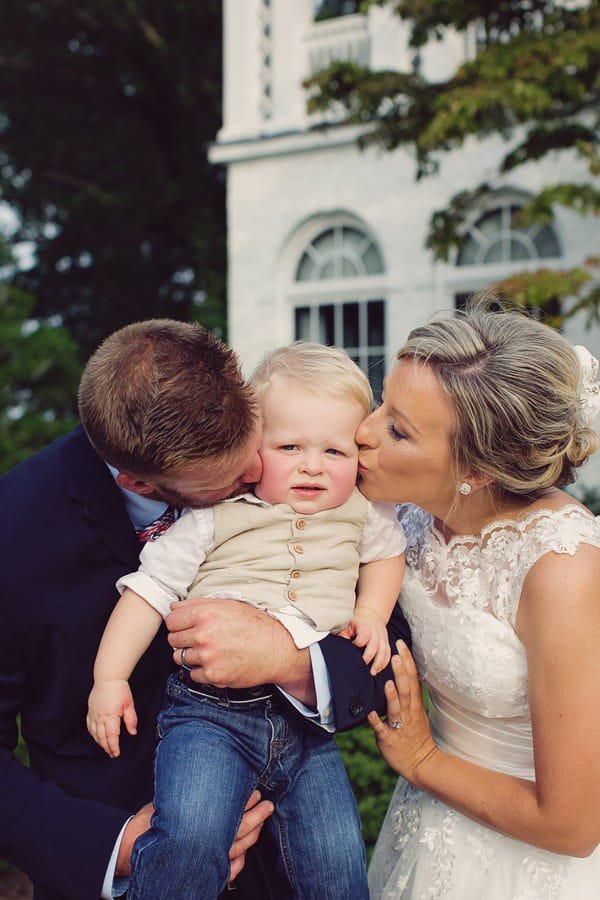 Bride and groom kissing pageboy on cheeks