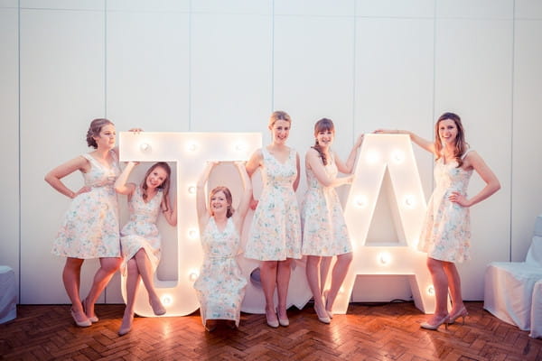 Bridesmaids posing with illuminated letters