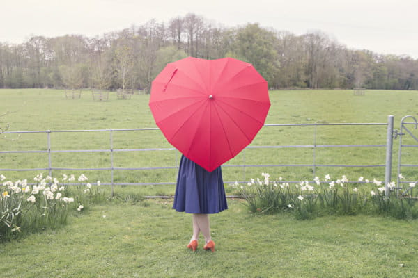 Bride behind red heart umbrella