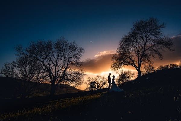 Bride and groom standing on hill at night - Picture by Andrew Keher Photography